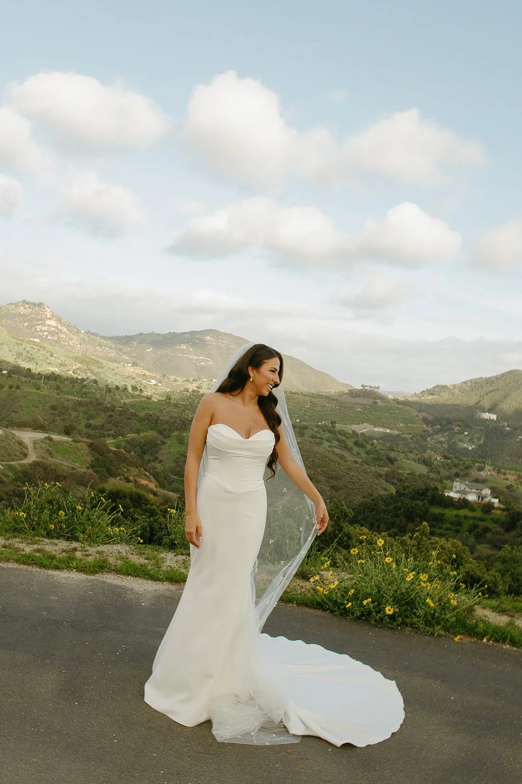 A bride taking photos in front of mountains at her mountain wedding venues