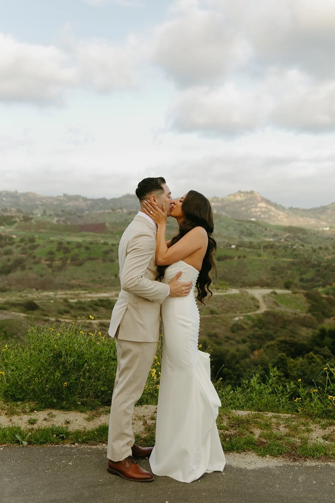 A groom and bride taking photos in front of mountains at their mountain wedding venue
