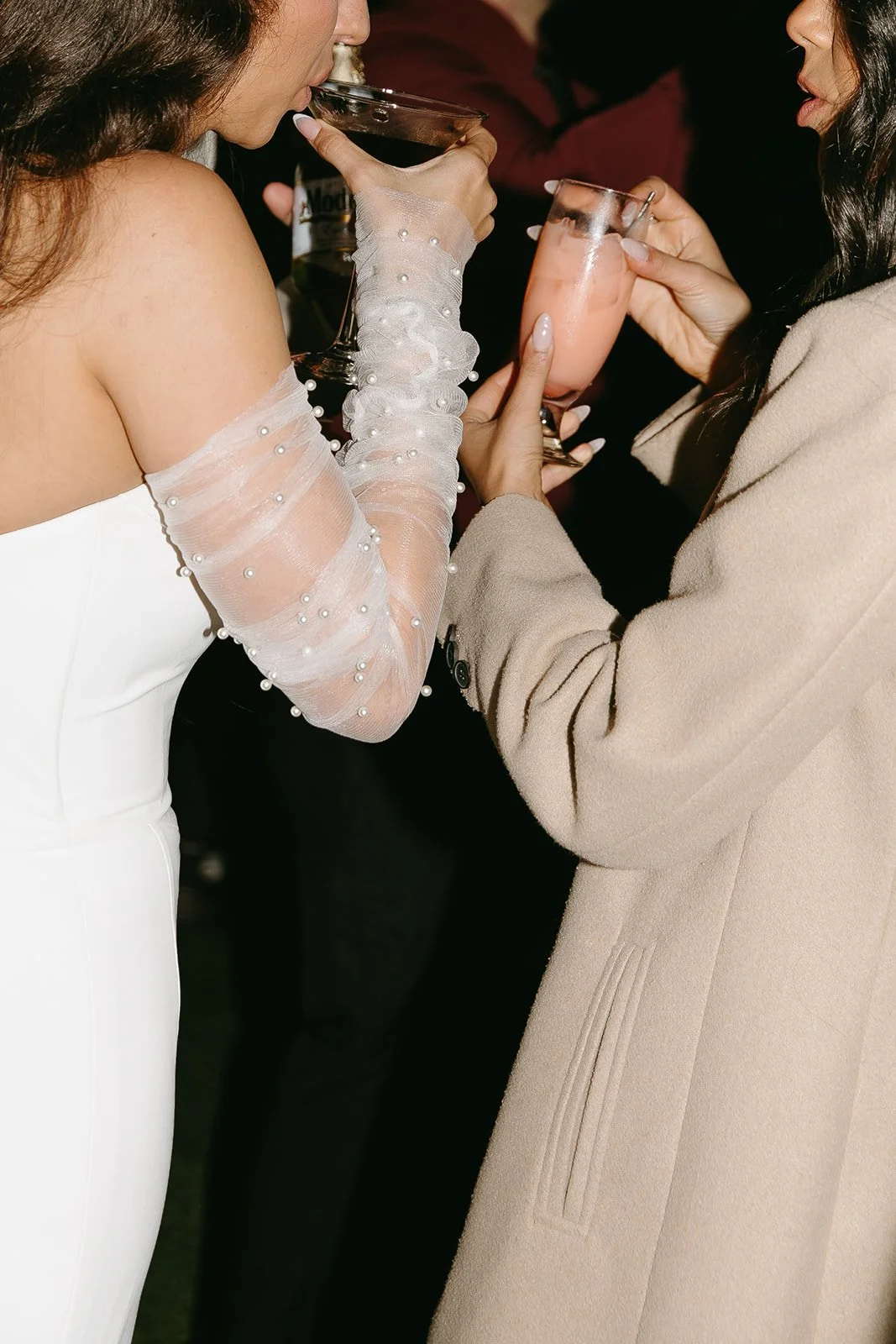 A bride drinking a cocktail with guests at her wedding reception