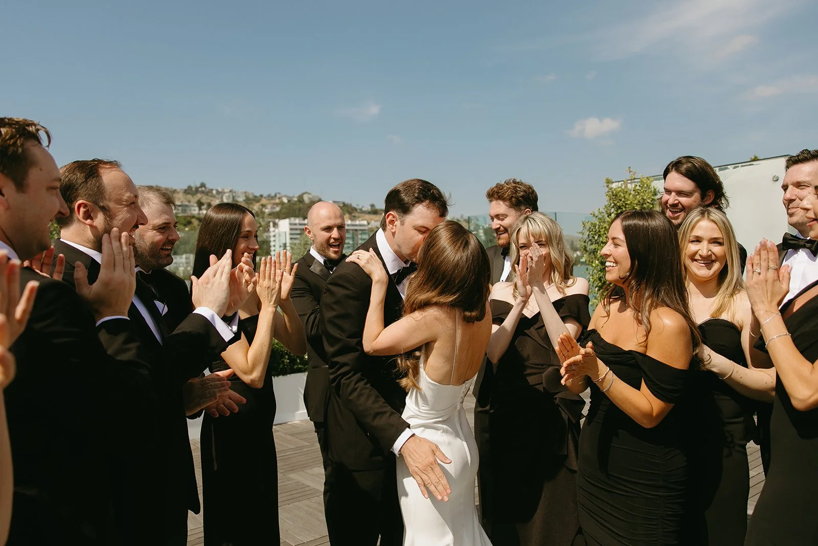 A wedding party cheering while a bride and groom kiss