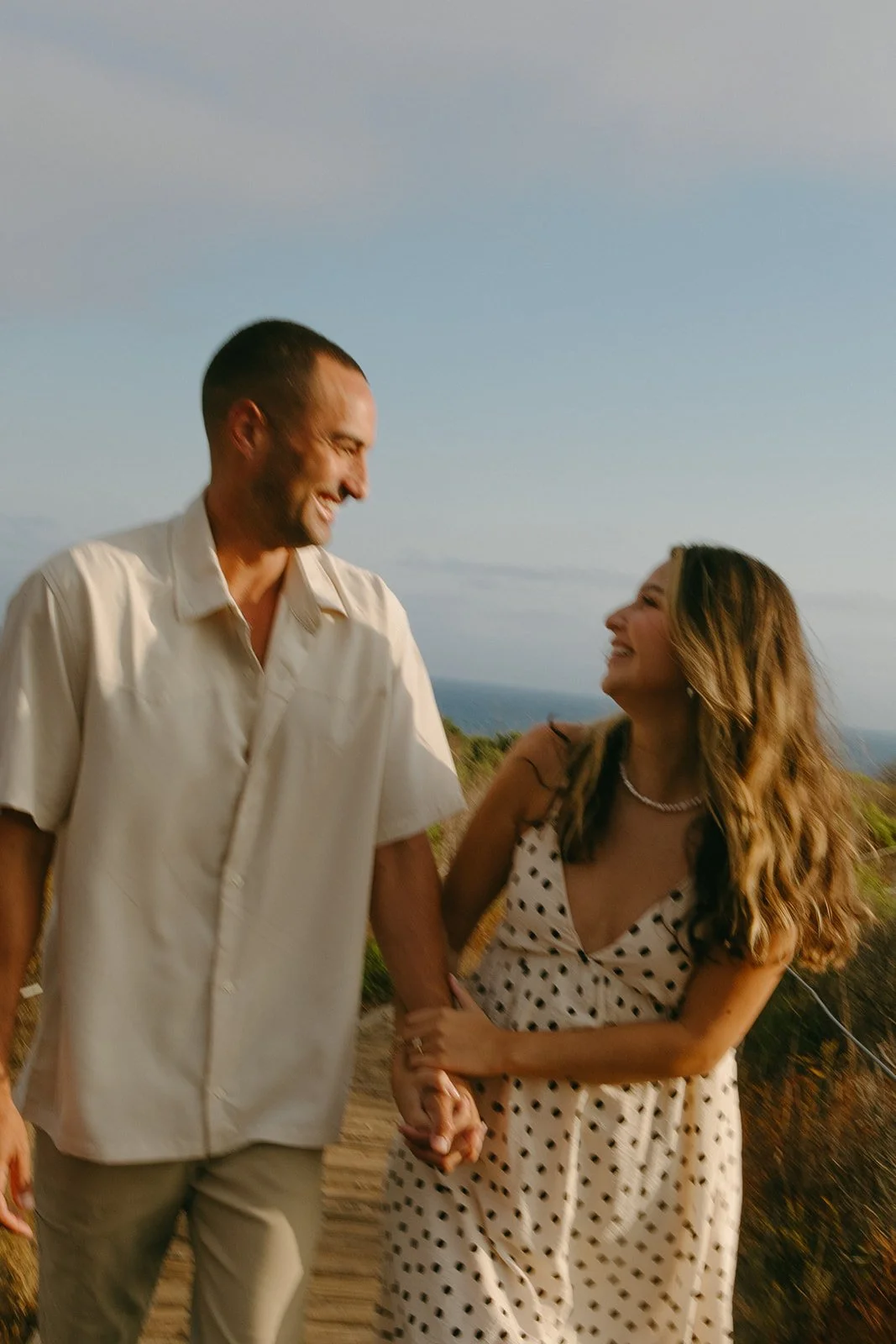A couple laughing at each other during beach engagement photos