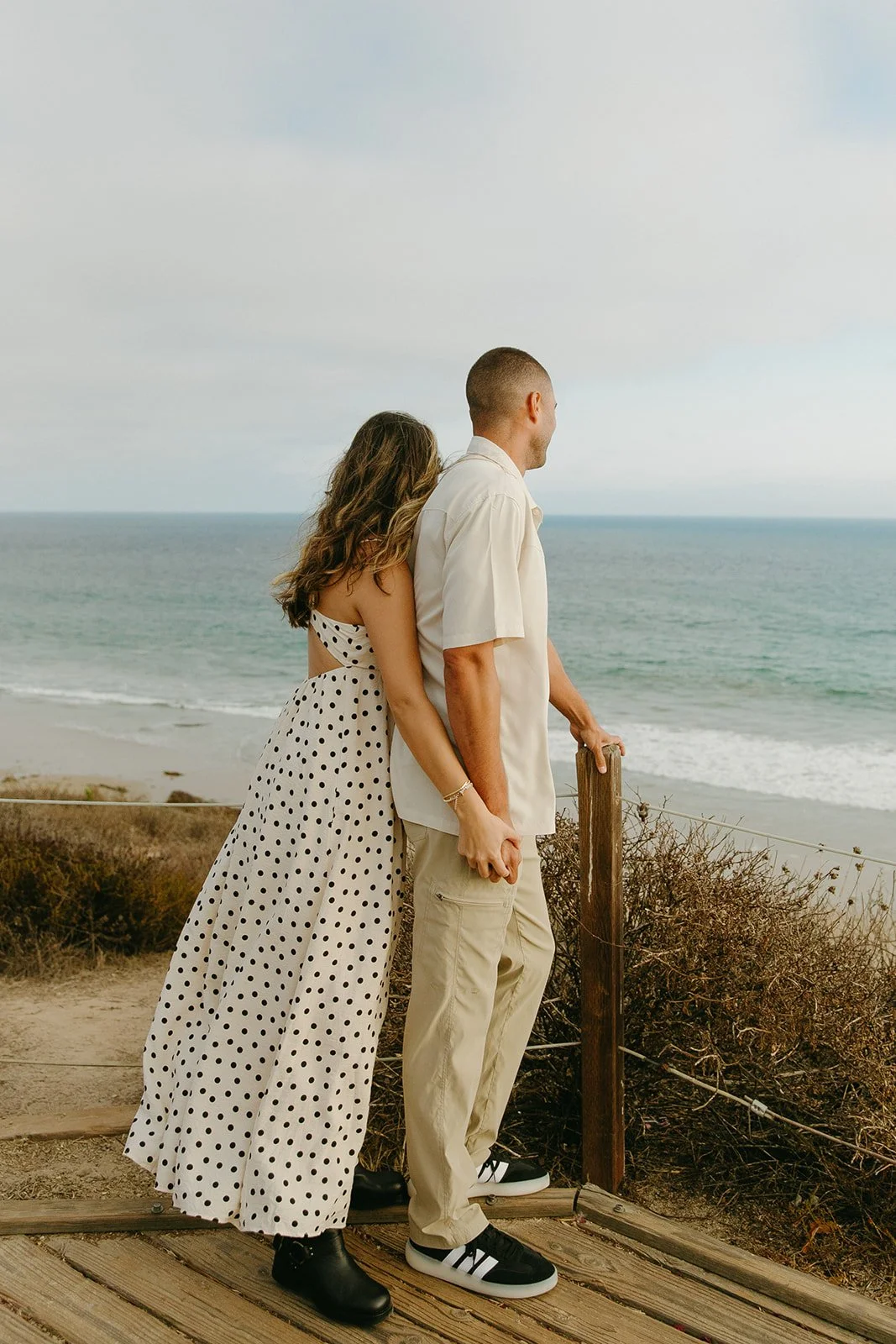 A couple posing for engagement pictures looking out at the ocean