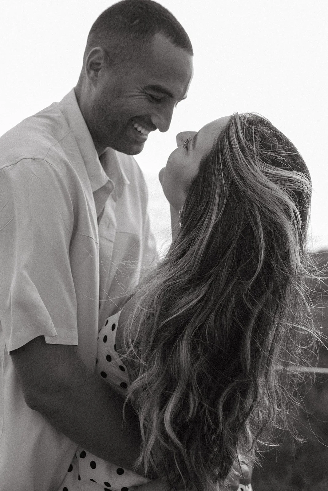 A couple leaning in for a kiss, wearing engagement photo outfits that show what to wear for engagement photos