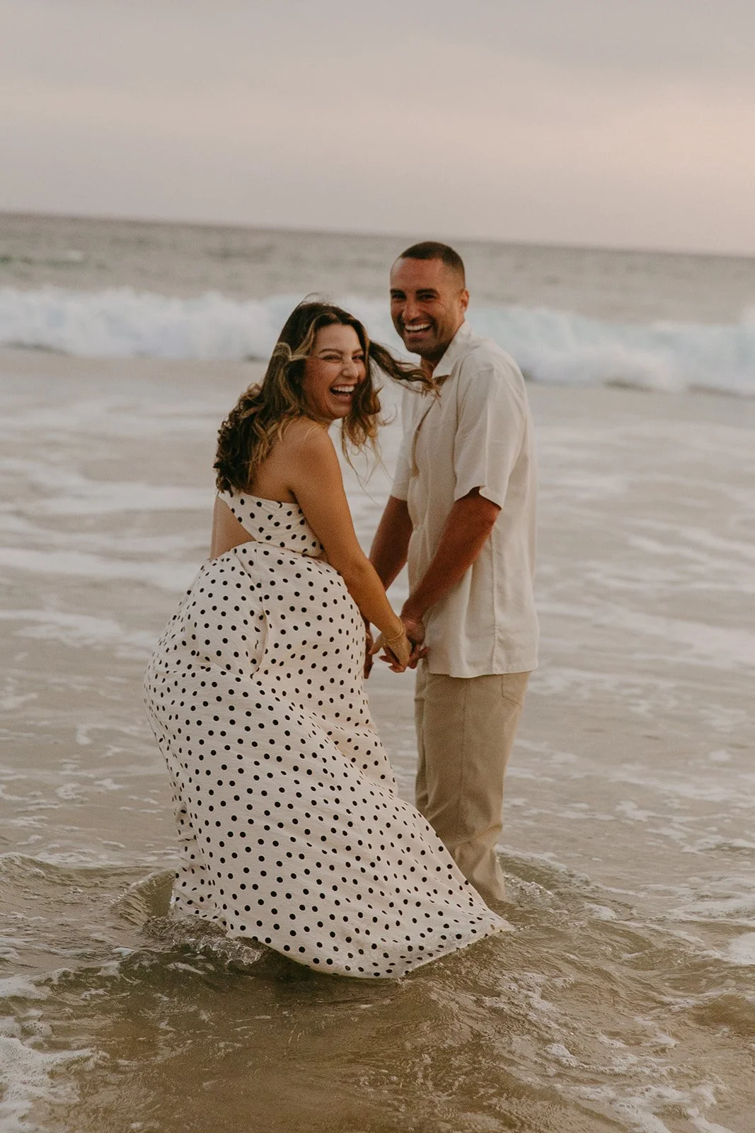 A couple in the ocean showing what to wear for engagement photos