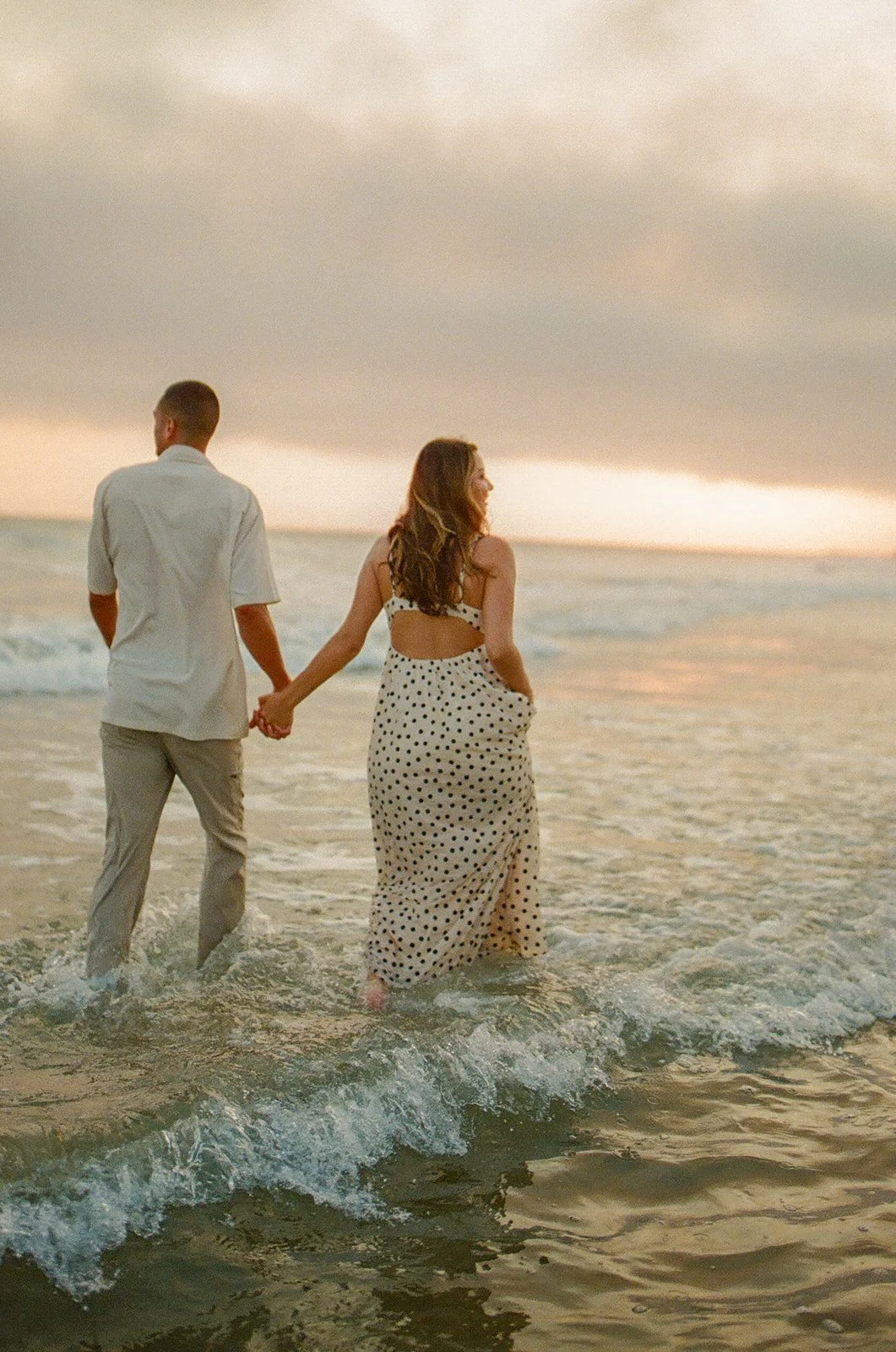 A couple walking in the ocean during beach engagement photos