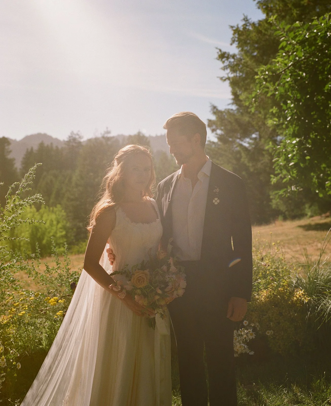 A bride and groom posing for garden wedding photos in a field
