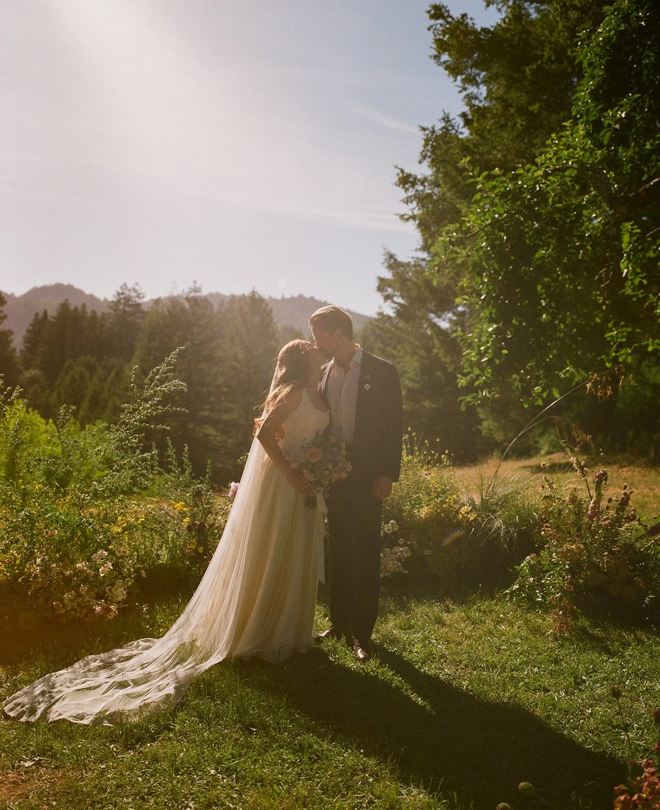 A bride and groom posing for garden wedding photos in a field