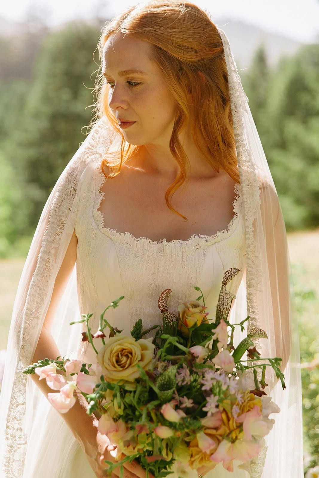 A bride posing for bridal portraits in a garden wedding dress and veil