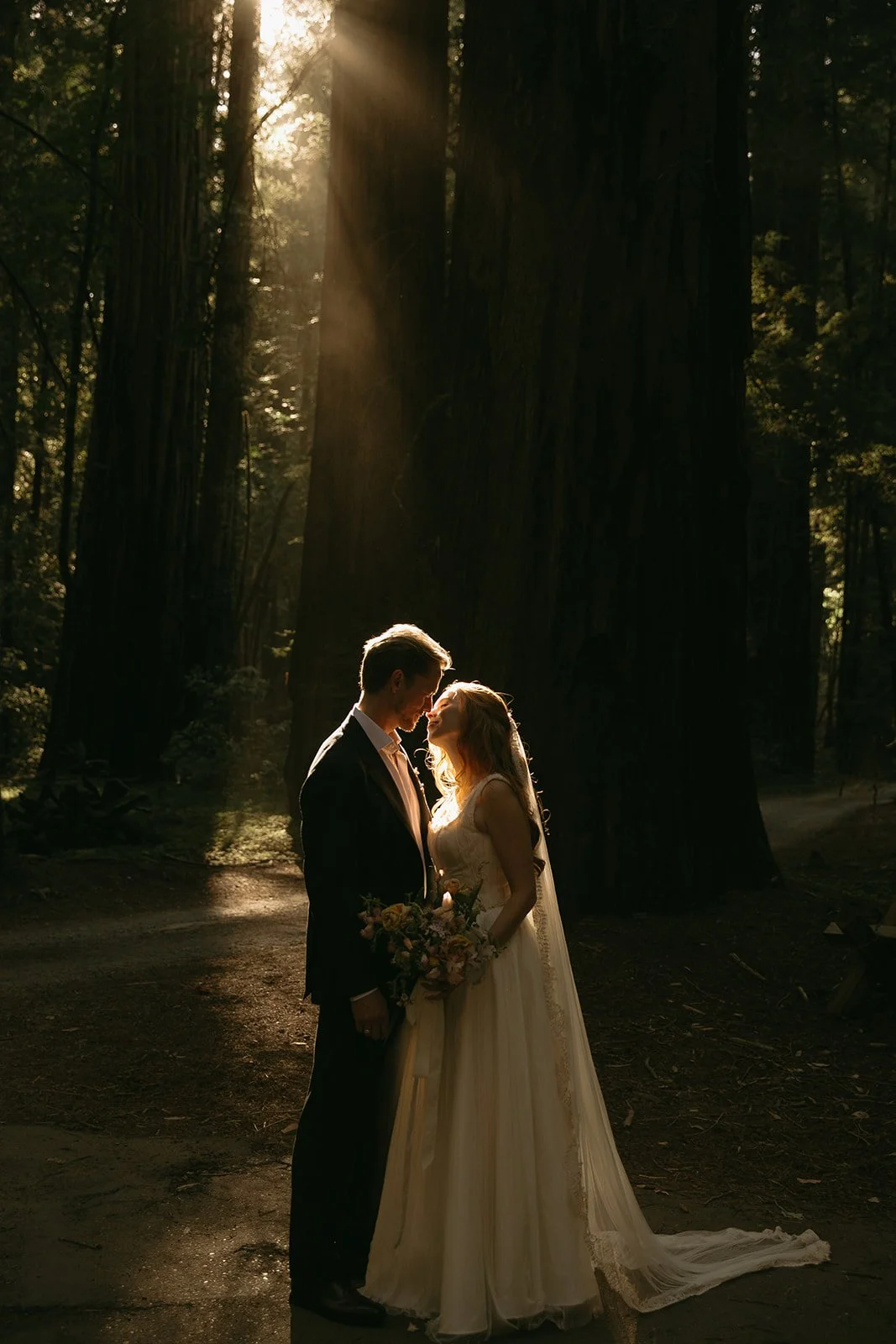 A bride and groom posing for wedding photos in a forest