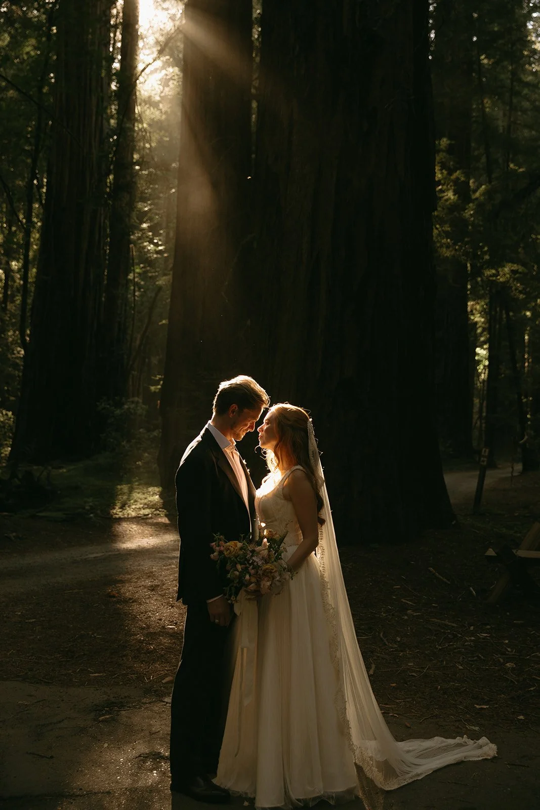 A bride and groom posing for wedding photos in a forest