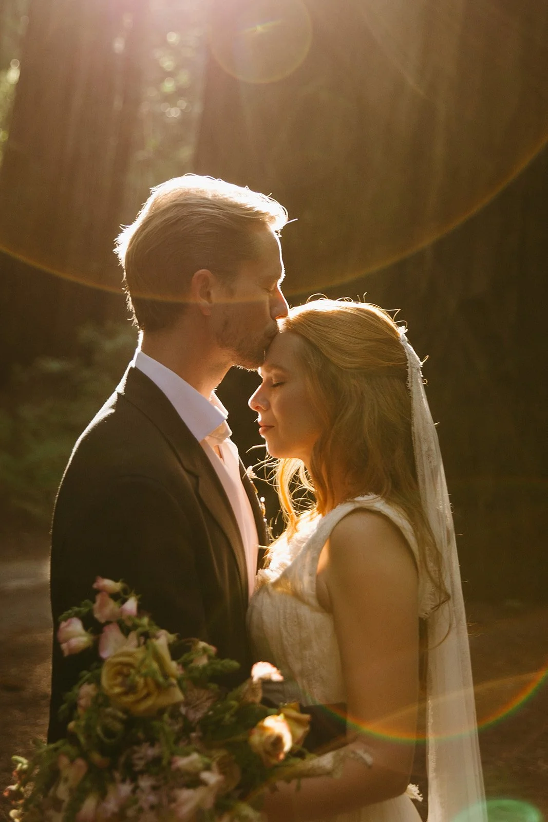 A bride and groom posing for wedding photos in a forest