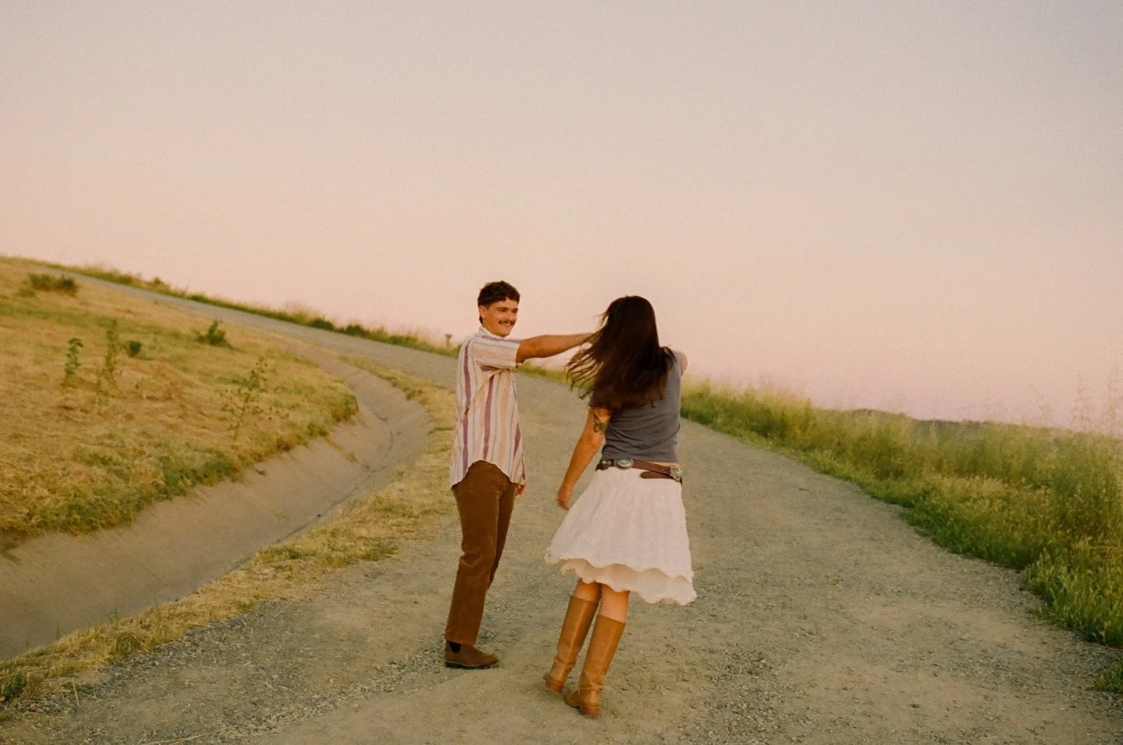 A couple dancing on a dirt road for film engagement photos