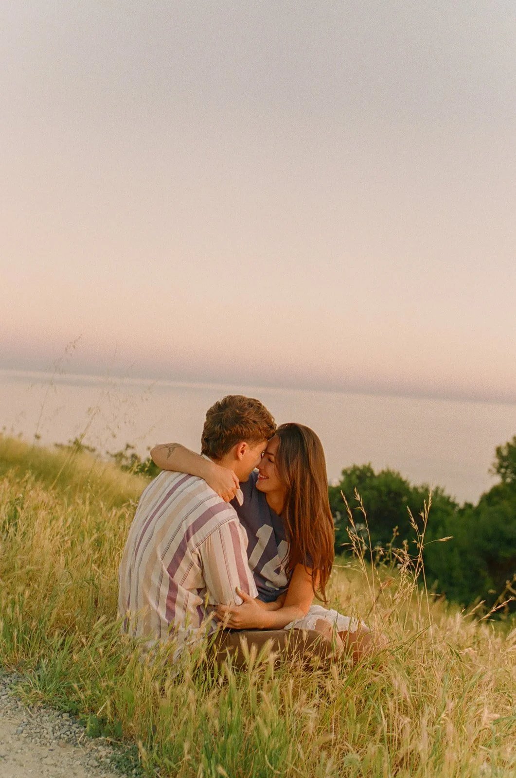 A couple posing for engagement photos at a spot overlooking Laguna Beach