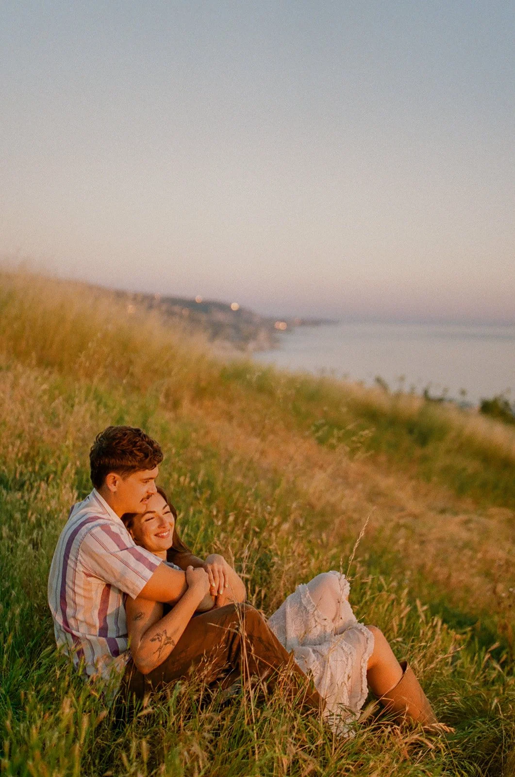 A couple posing for engagement photos at a spot overlooking Laguna Beach