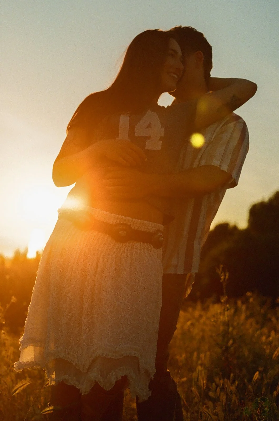 A couple posing for film engagement photos with the sun hitting behind them