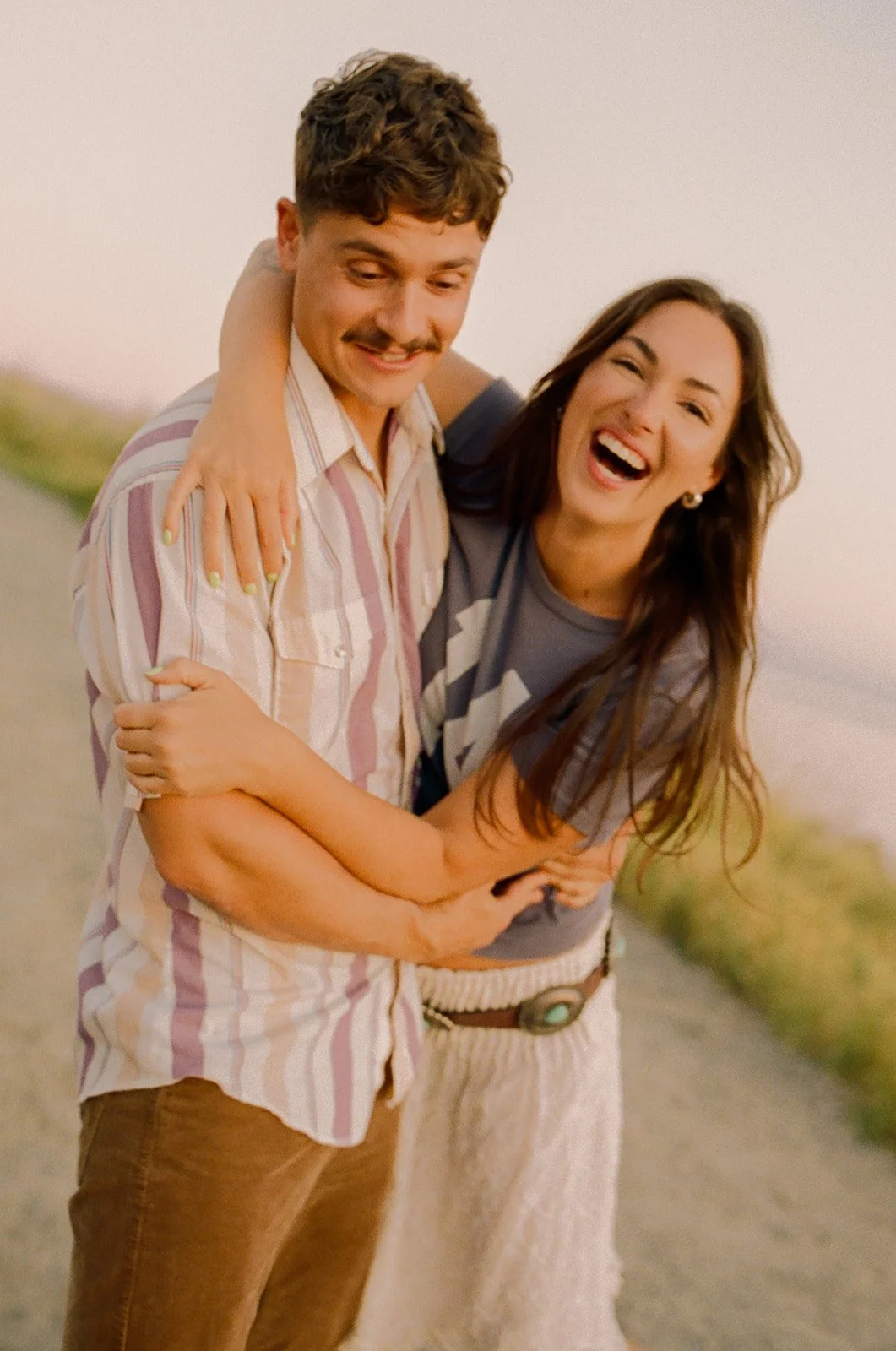 A couple laughing in film engagement photos at Laguna Beach