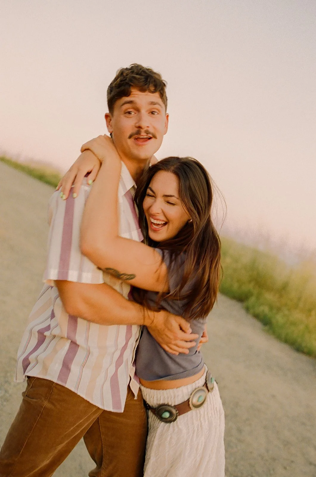 A couple laughing in film engagement photos at Laguna Beach