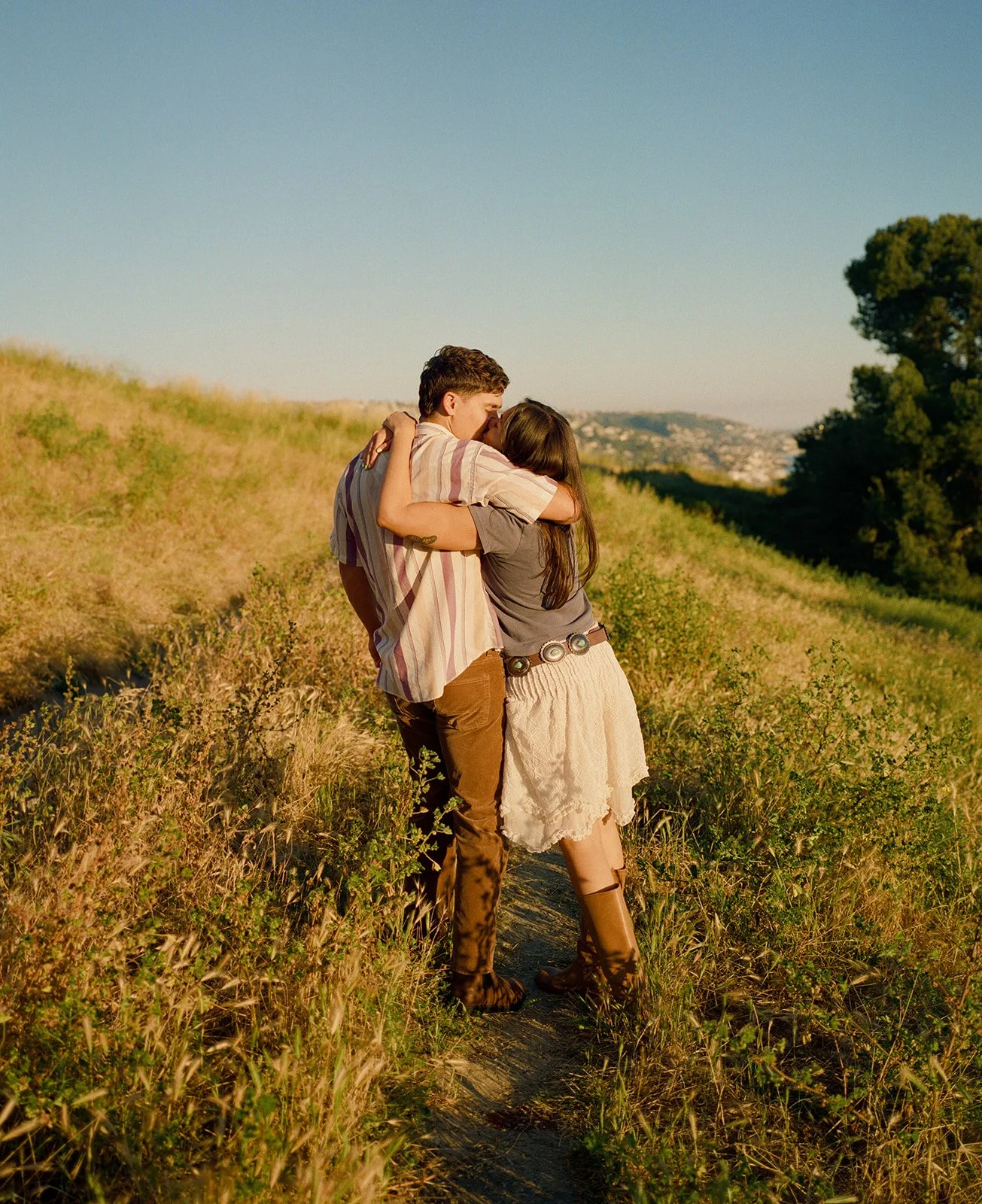 A couple kissing in film engagement photos in a field