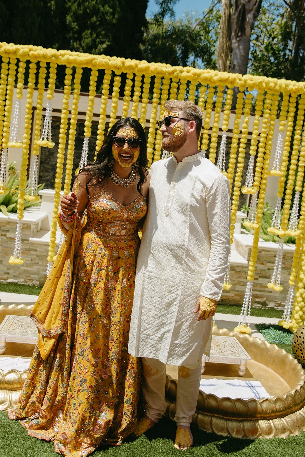 A bride and groom with turmeric on their faces