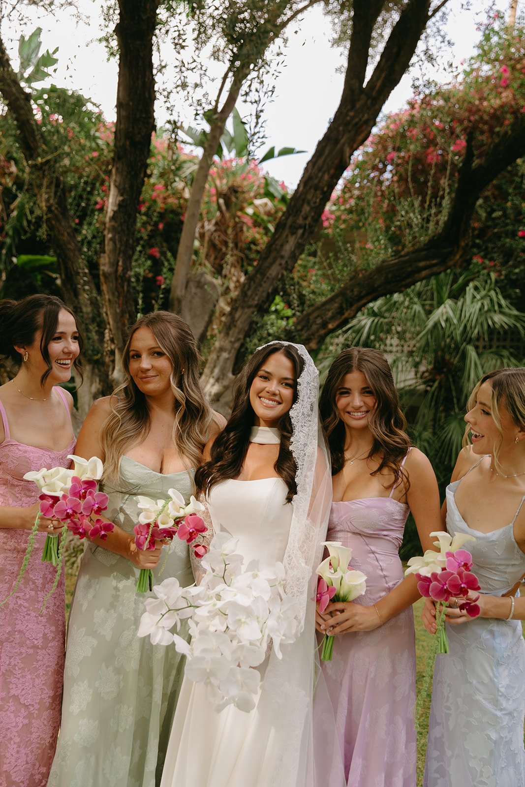 a bride and bridesmaids in mismatched pastel bridesmaid dresses perfect for palm springs weddings