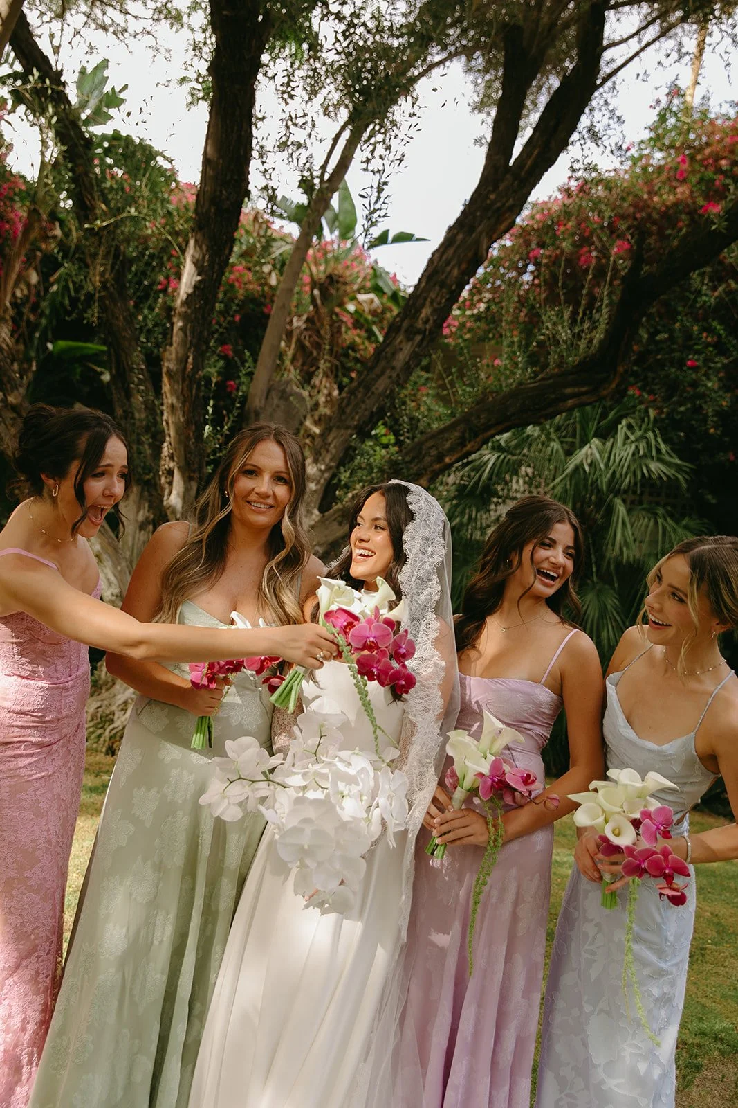 a bride and bridesmaids in mismatched pastel bridesmaid dresses perfect for palm springs weddings