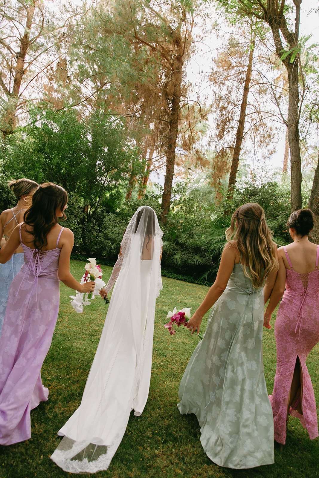 a bride and bridesmaids in mismatched pastel bridesmaid dresses perfect for palm springs weddings