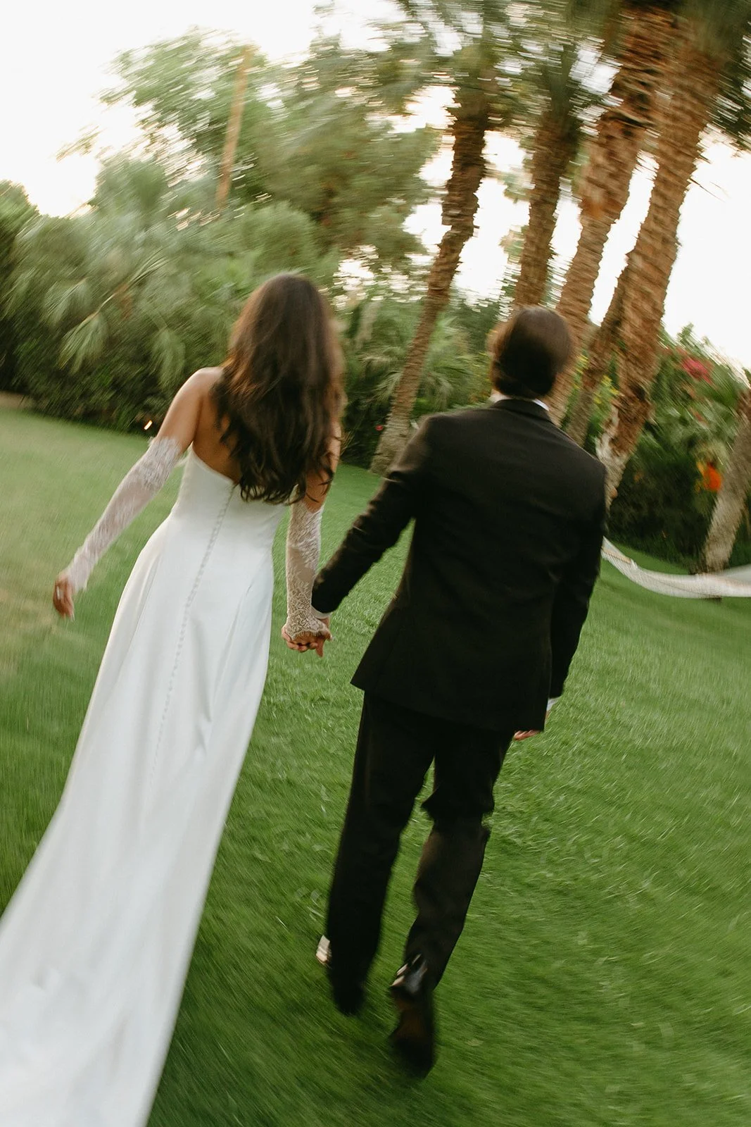 A bride and groom walking away from the camera holding hands