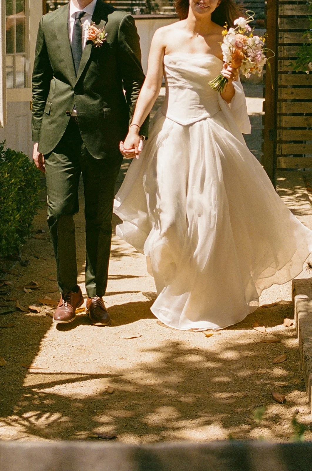 A bride and groom walking hand in hand at their small wedding
