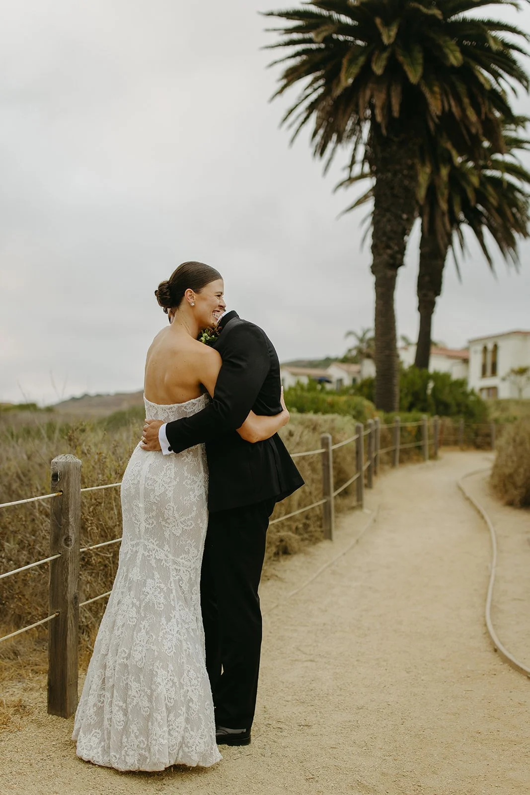 A bride and groom hugging on a trail at their wedding venue