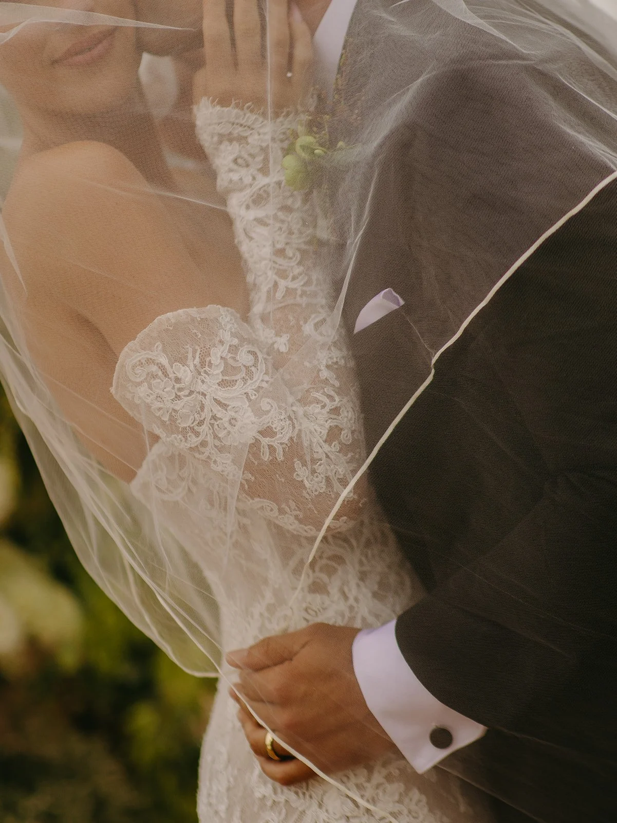 A bride and groom taking wedding portraits underneath a veil