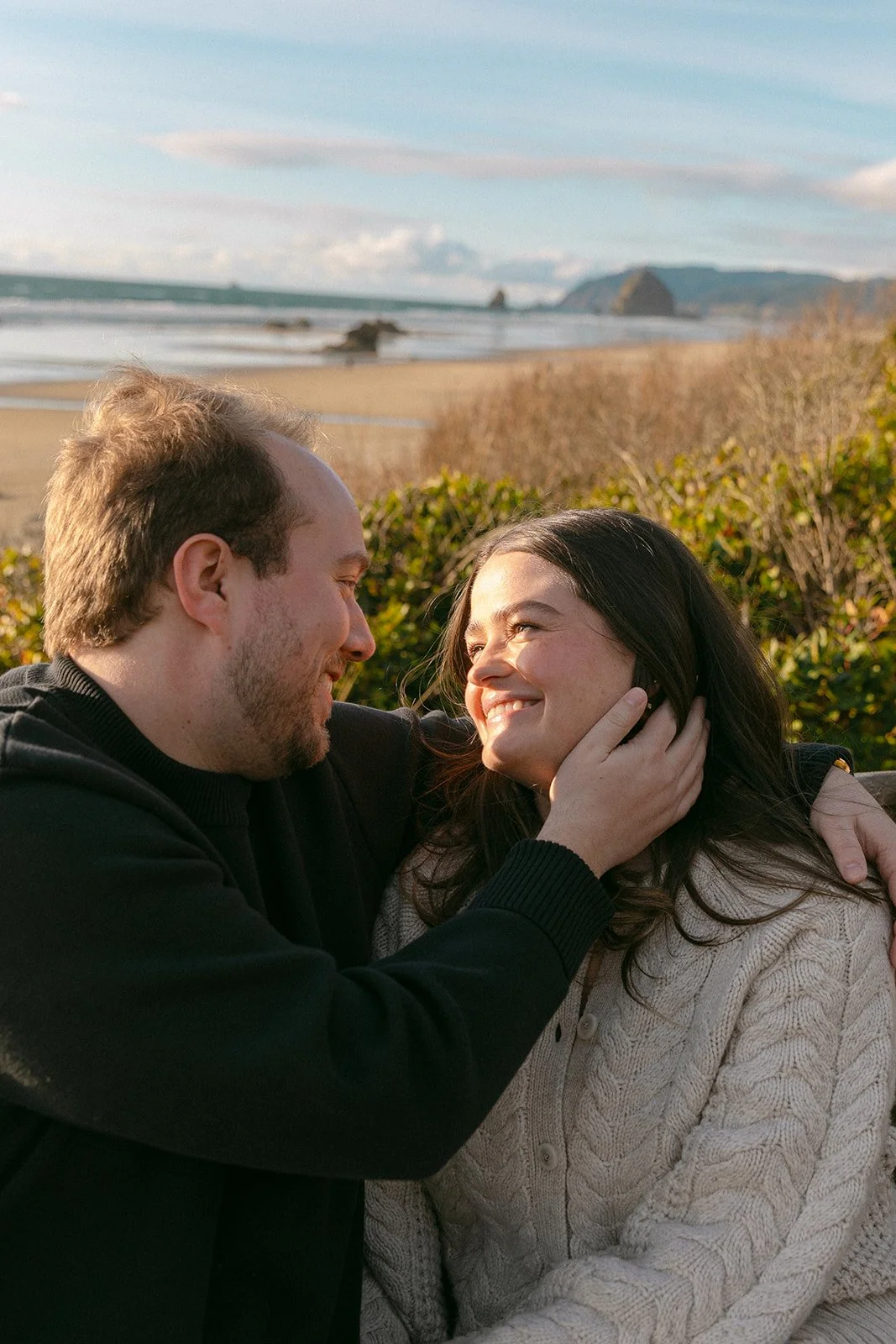 A couple taking outdoor engagement photos at Cannon Beach