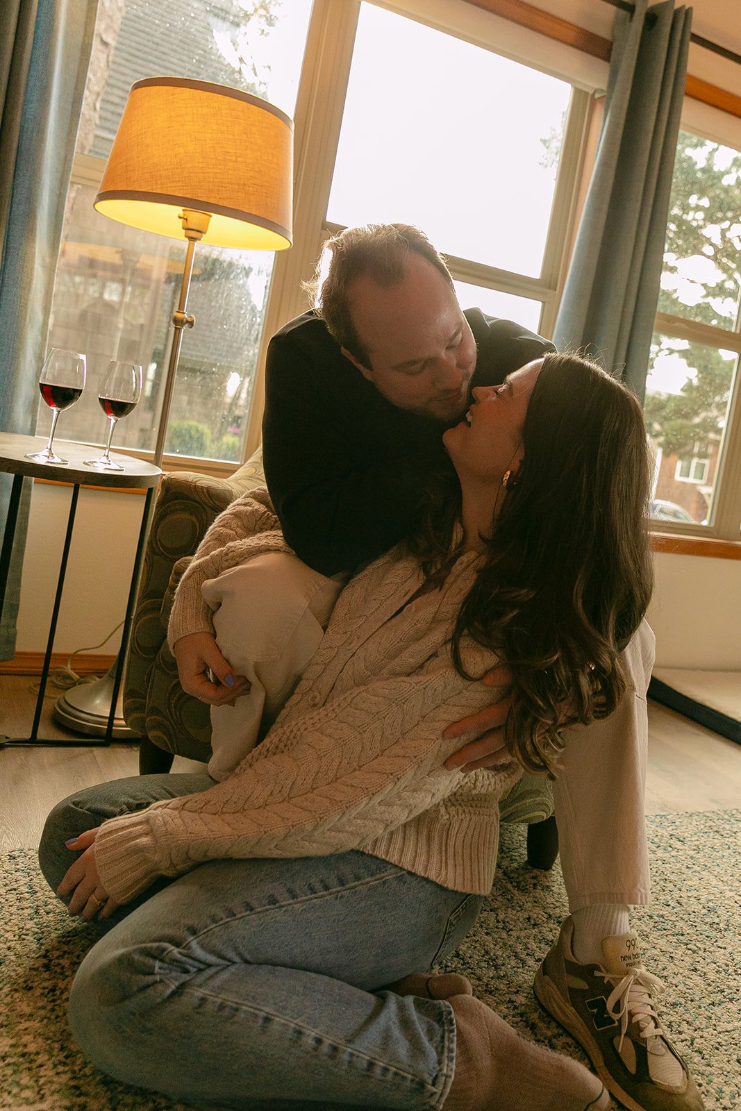 A couple taking indoor engagement photos in a family home after choosing where to take engagement photos