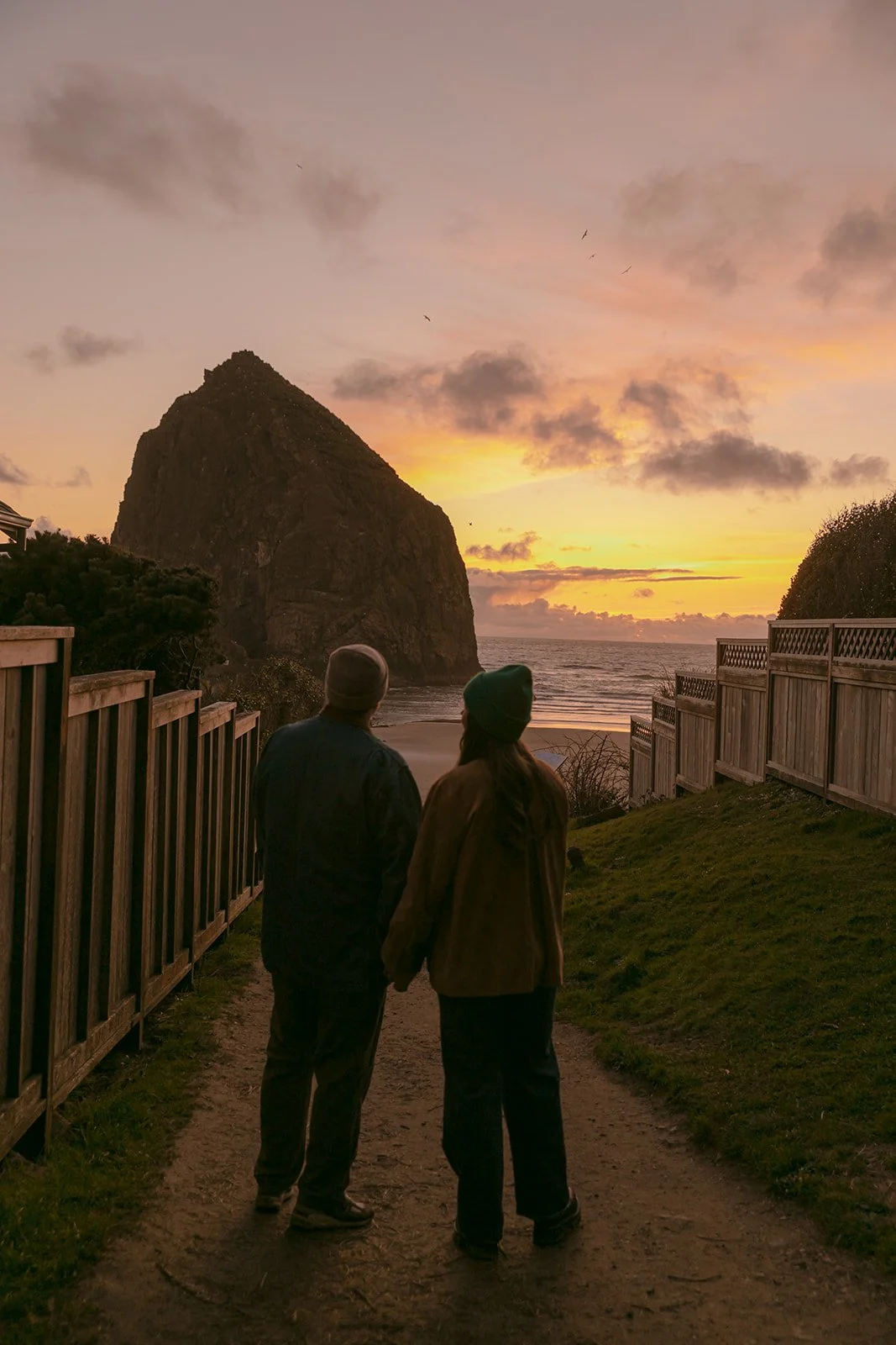A couple taking sunset engagement photos on cannon beach