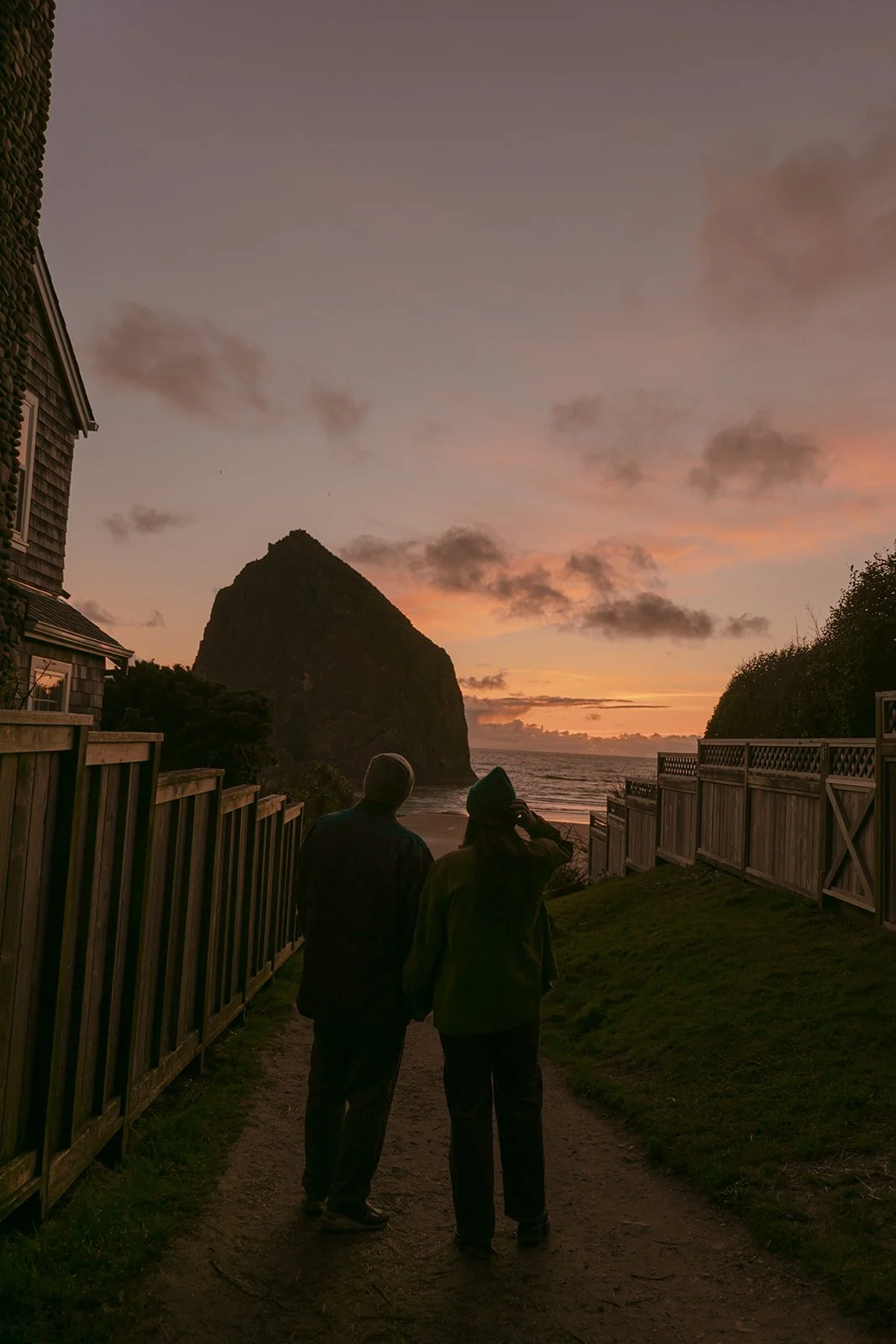 A couple taking sunset engagement photos on cannon beach
