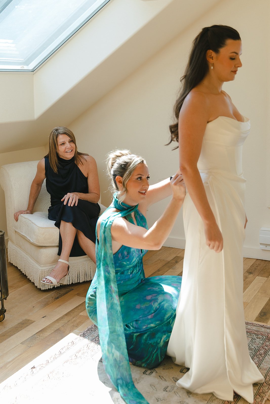 Bridesmaids buttoning a bride's wedding dress
