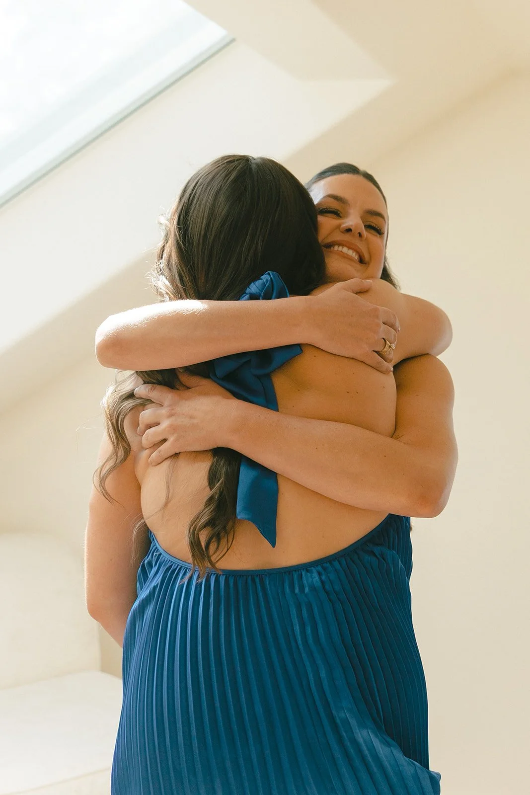A bridesmaid hugging a bride in a candid wedding photo