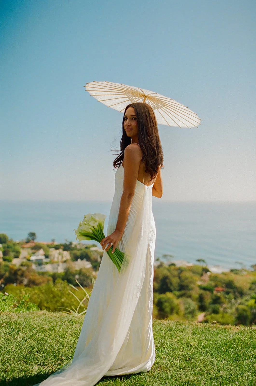 A bride posing for portraits with a parasol