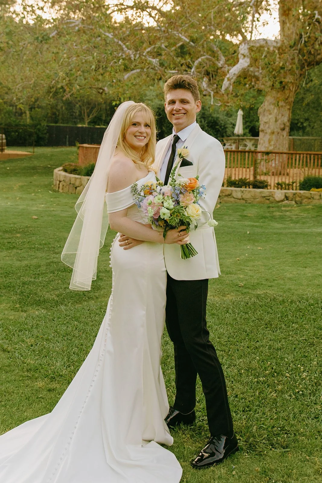 A bride and groom taking portraits on a lawn