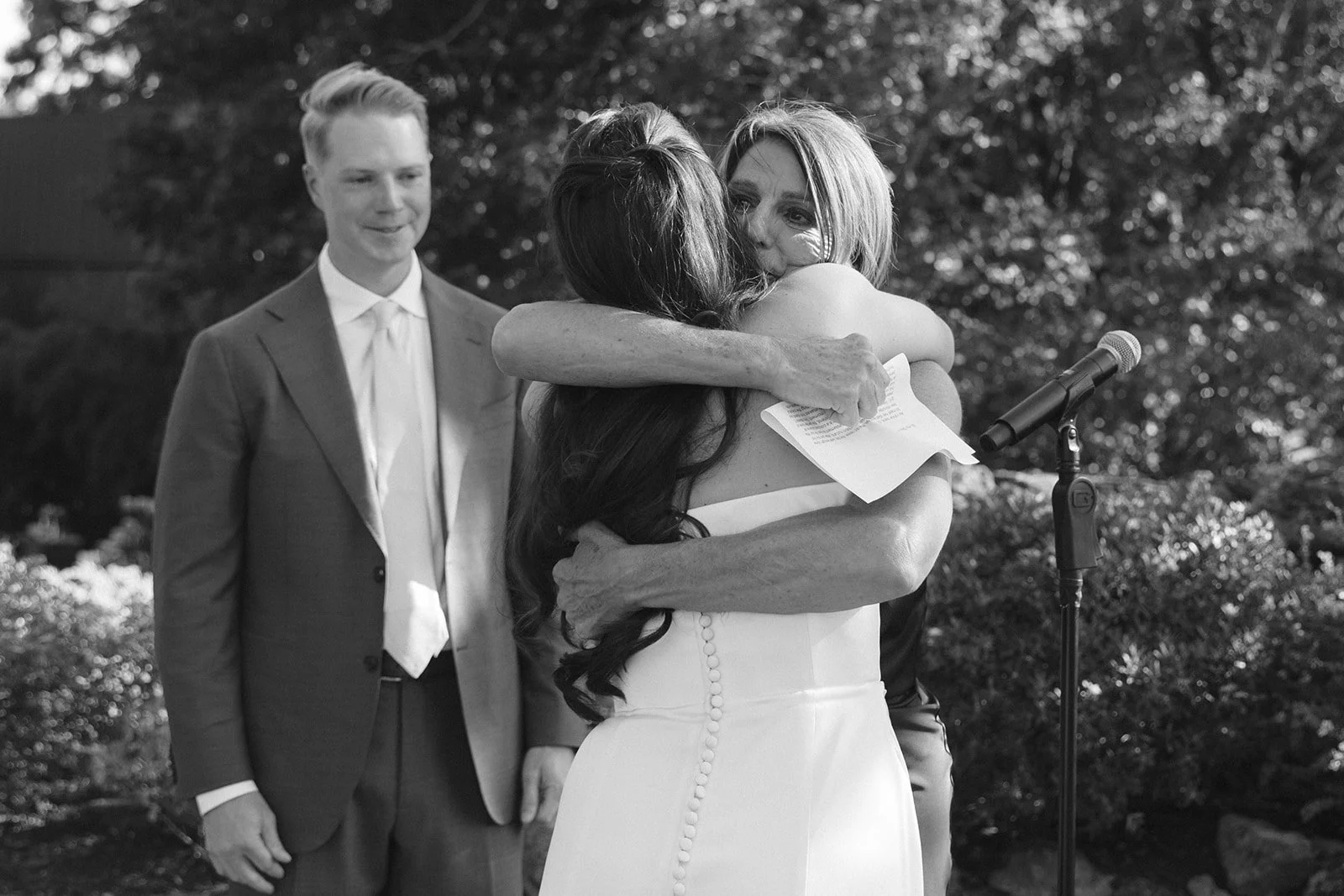 A bride hugging her mom after a ceremony speech, showing memorial ideas for weddings