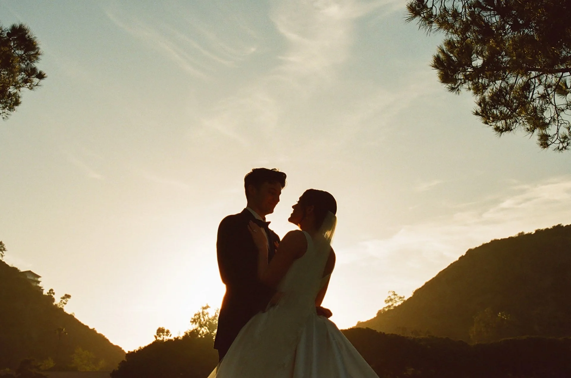 Bride and groom silhouetted against the sunset during romantic portraits at The Ranch at Laguna Beach wedding golf course.