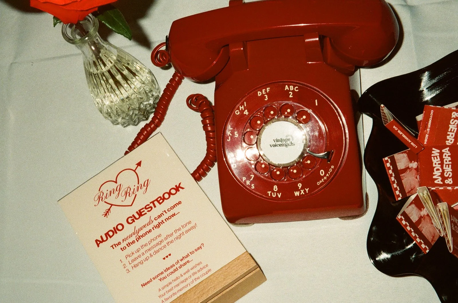 A vintage red rotary phone set up as an audio guestbook on a table at The Revery LA for guests to leave messages.