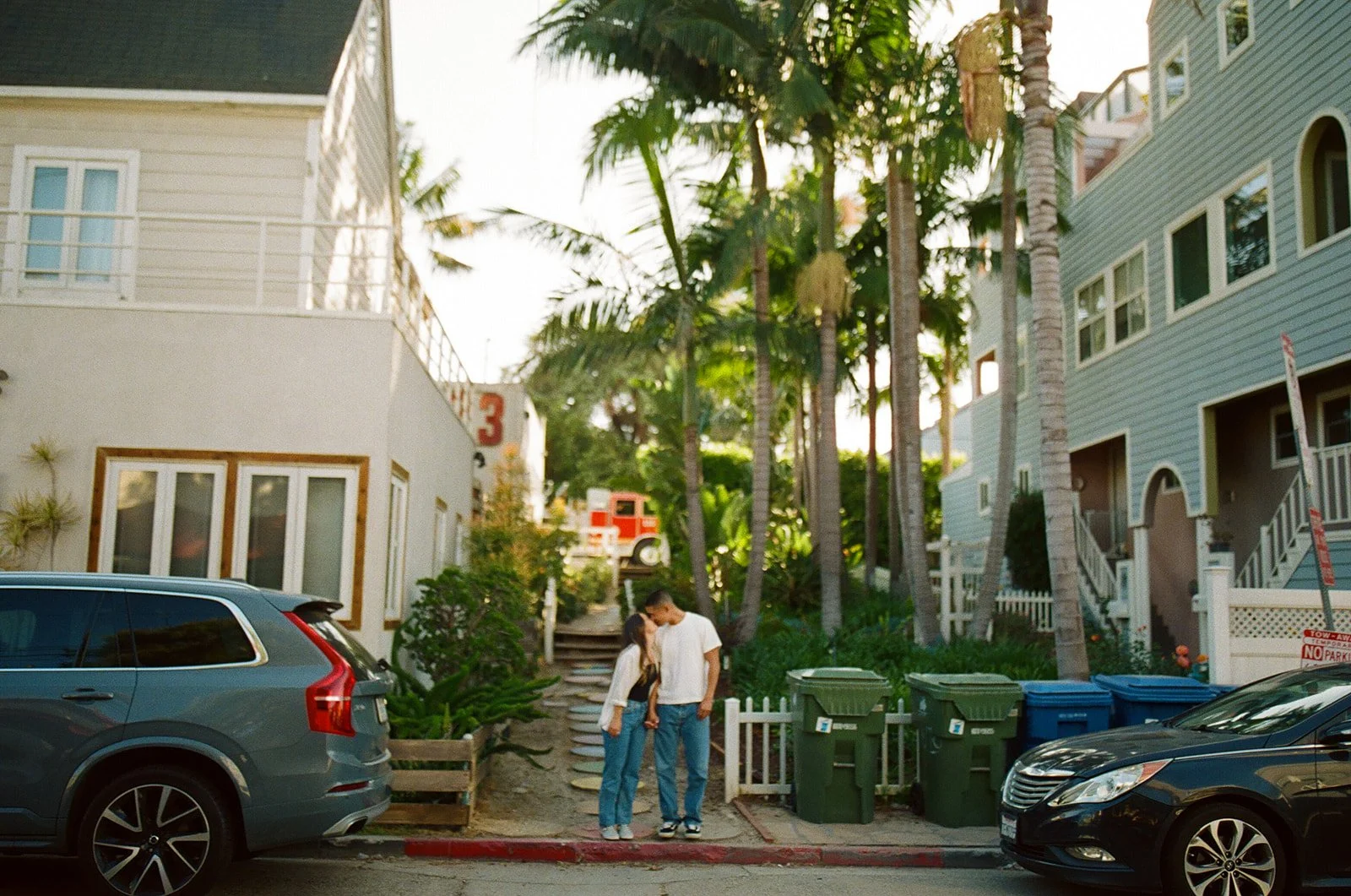 A candid neighborhood street moment at Venice Beach Photoshoot Locations with palm trees and colorful homes in the background.