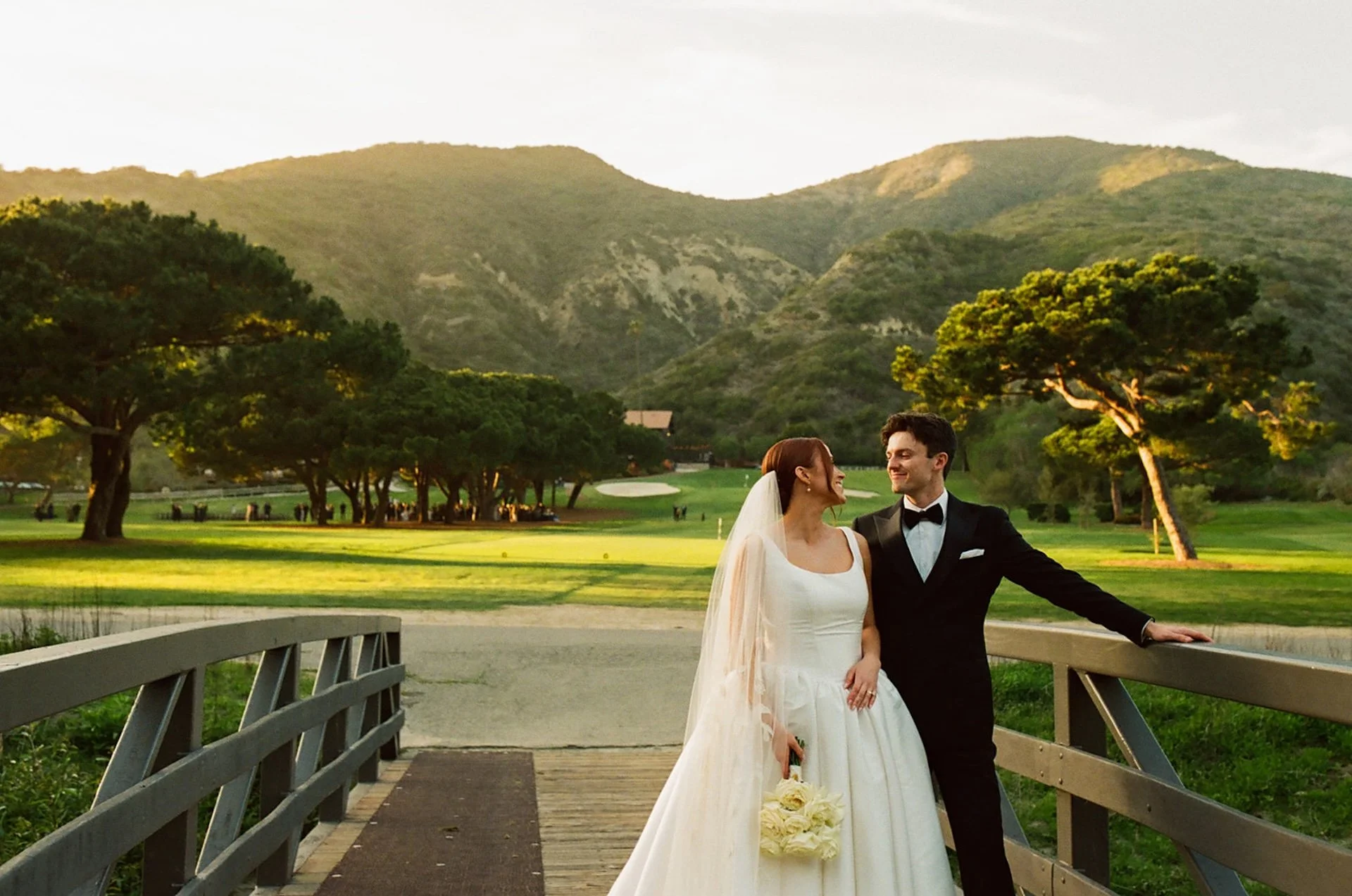 Bride and groom on the bridge overlooking the golf course during sunset portraits at The Ranch at Laguna Beach wedding.