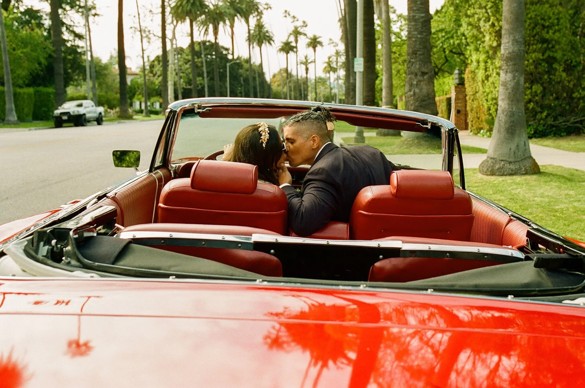 Newlyweds kissing in the front seat of a red convertable during their Beverly Hills Courthouse Elopement portraits