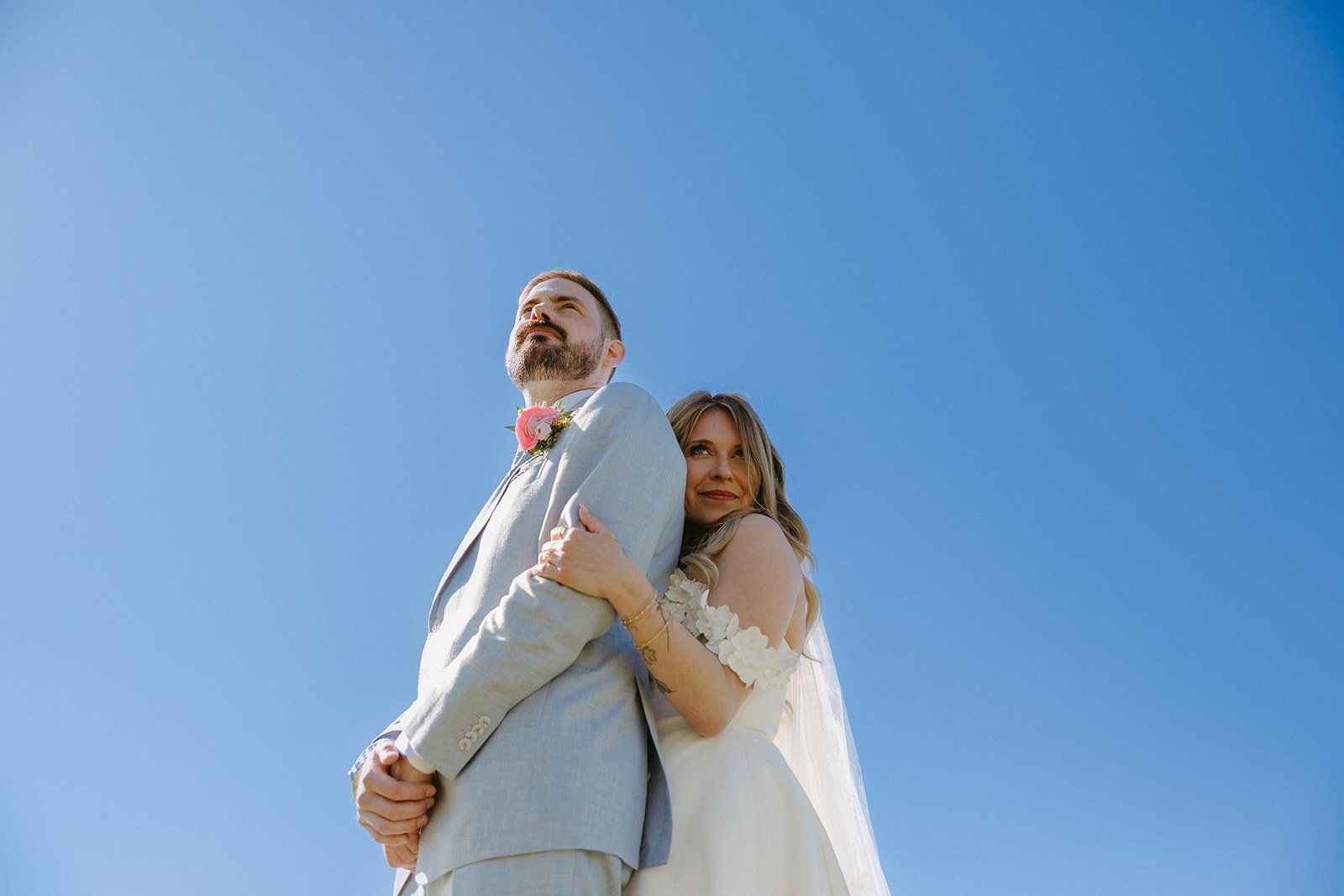 A bride and groom posing for colorful wedding photos with the sky as their backdrop