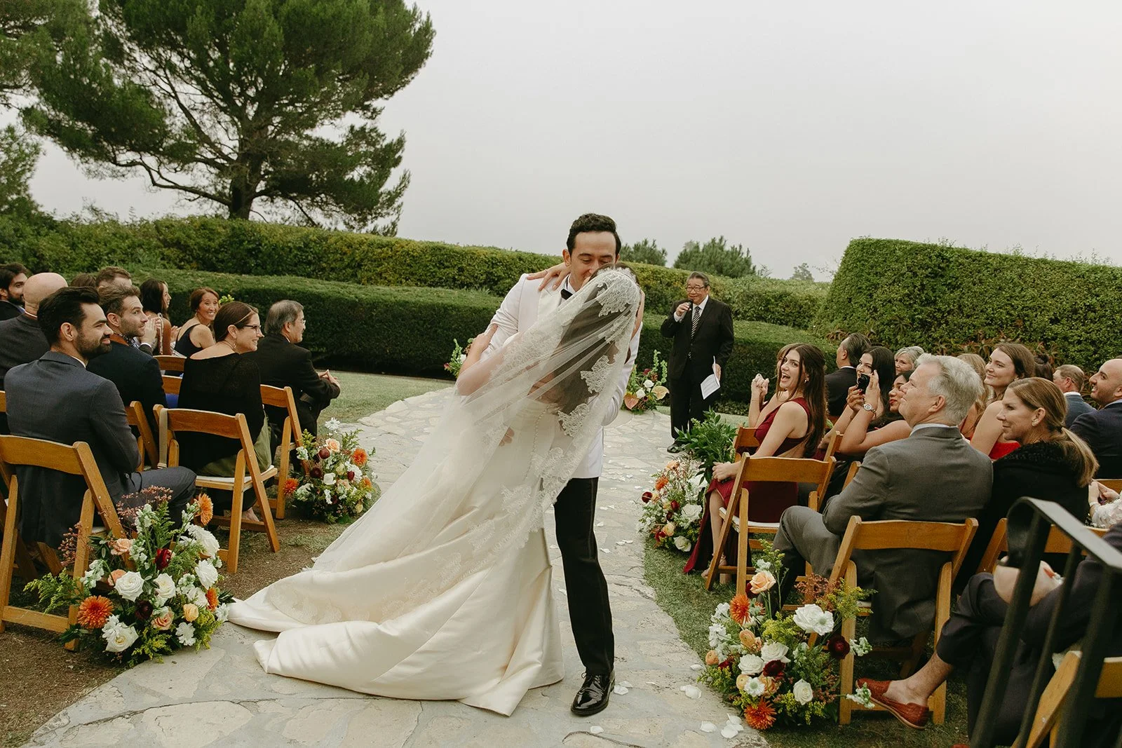 The couple sharing their first kiss down the aisle as guests look on at a Palos Verdes wedding venue.
