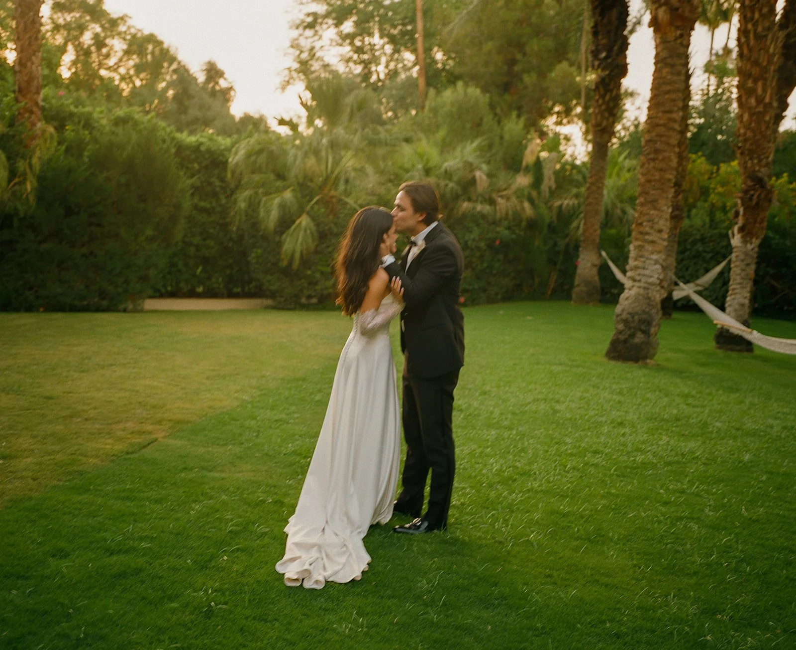A groom kissing a bride on the forehead