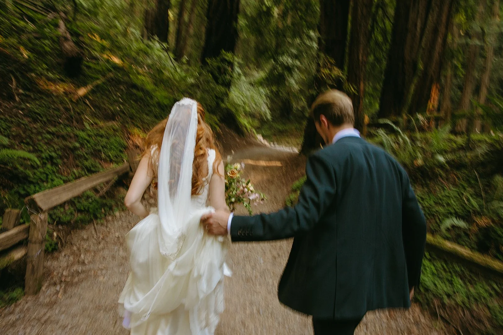 A bride and groom running through the forest in blurry wedding photos