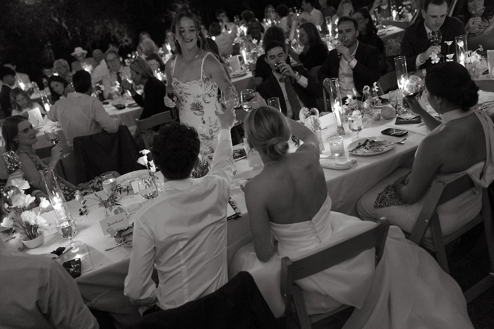 A bride and groom clinking glasses with guests at their wedding reception