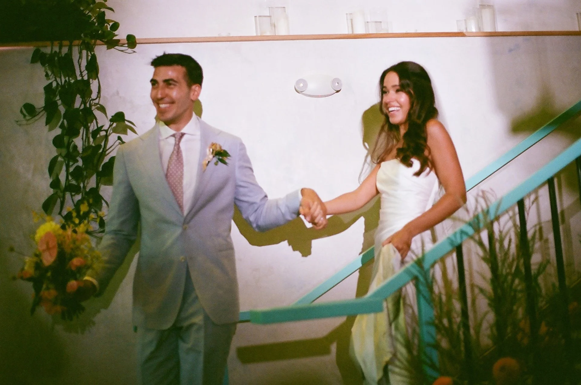 The groom leading the bride down the stairs and smiling at guests.